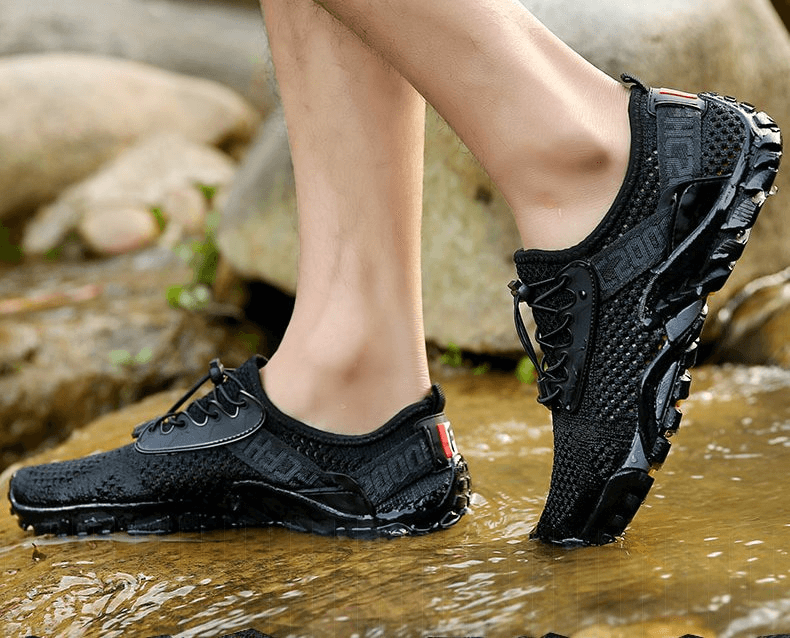 Breathable elastic camping shoes for men stepping on rocks, featuring breathable mesh, rubber outsole, and lace-up design.